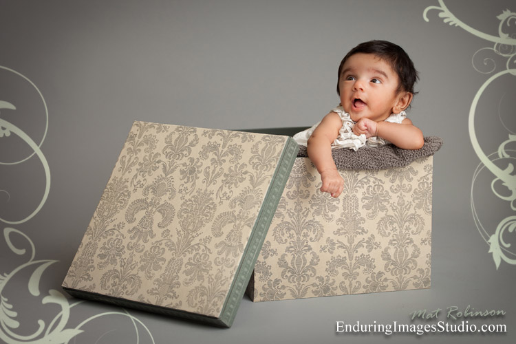 Newborn baby posed in a tiny little box for her photography portrait